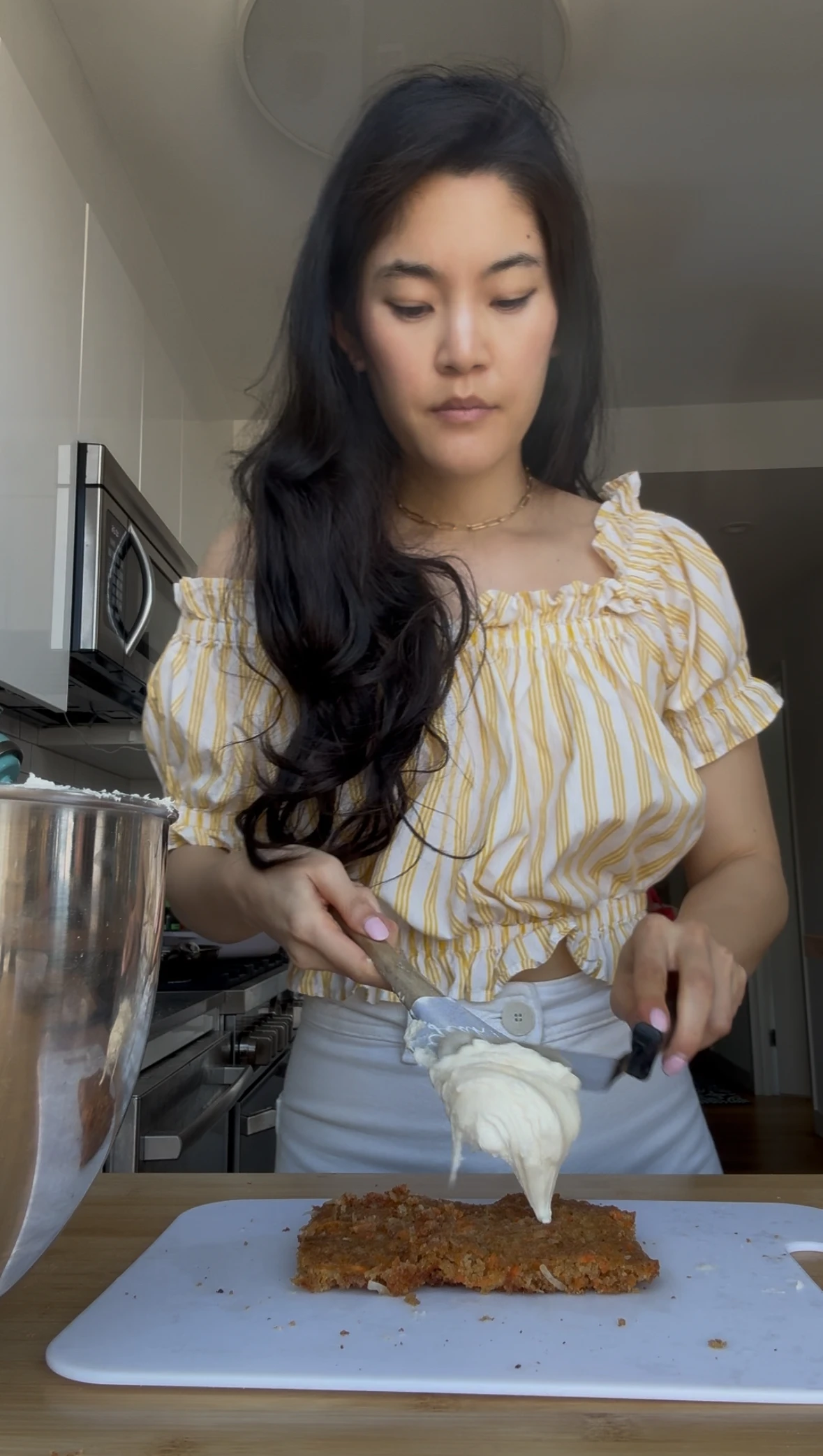 Erika Kwee spreads cream cheese frosting over a carrot cake